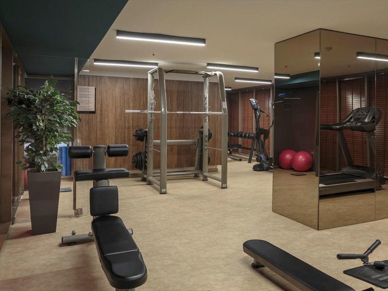 Moderní posilovna s různými tréninkovými zařízeními a zrcadlovou stěnou.