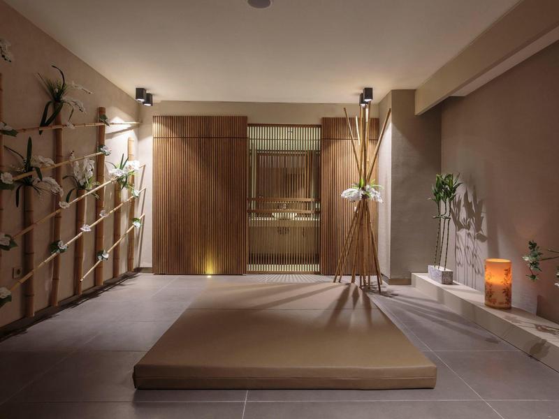 Pokoj wellness s masážním stolem, teplým osvětlením a uklidňující dekorací.