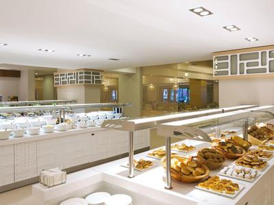 Hell eingerichteter Frühstücksraum mit Buffet und zahlreichen Gebäckstücken auf Metallgitter.
