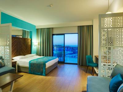 Modernes Hotelzimmer mit Doppelbett, großer Fensterfront und Sitzbereich.