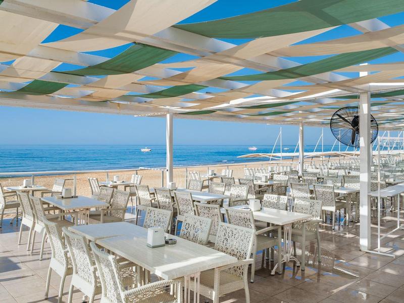 Restaurace terasa s výhledem na moře a modro-bílou pergolou.