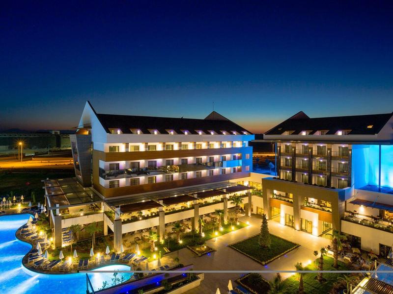 Moderní hotel v noci s osvětleným bazénem a teplým světlem.