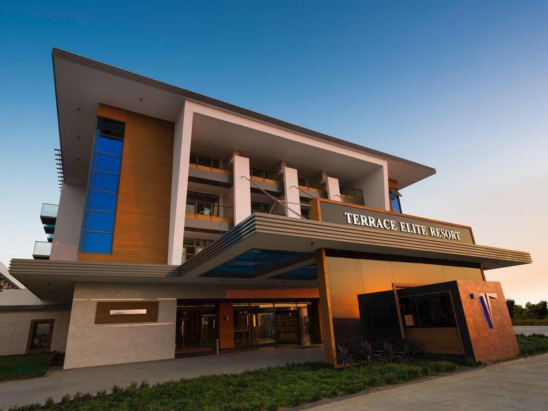 Moderní budova hotelu s terasou při západu slunce.