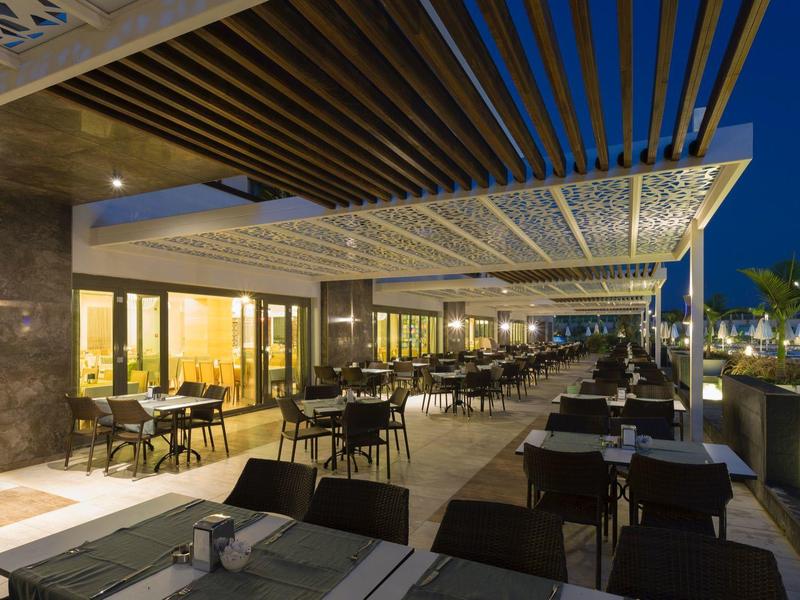 Elegantní terasa hotelové restaurace s stoly a židlemi pod noční oblohou.