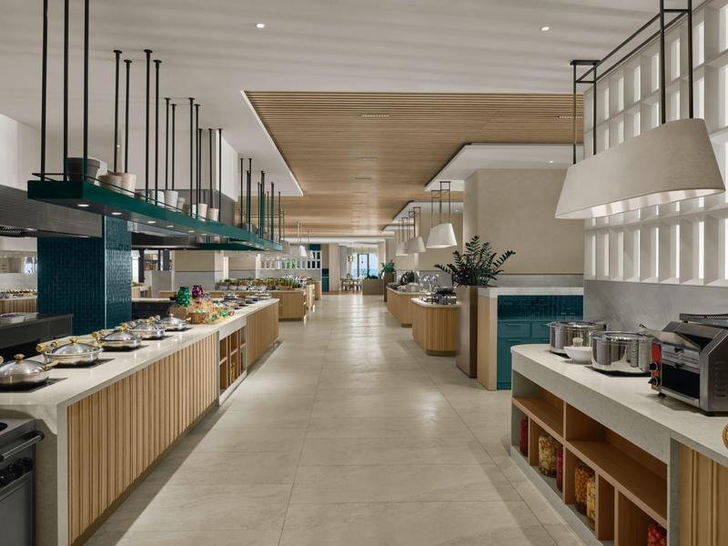 Moderní prostorná hotelová jídelna s bufetem a prostřenými stoly.