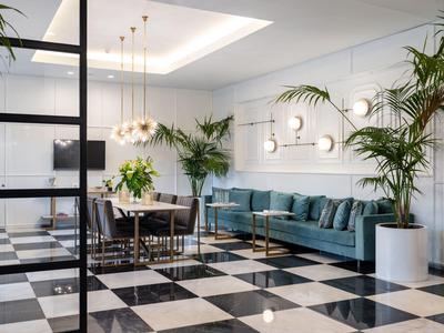 Moderner Hotel-Loungebereich mit gefliesten Schwarz-Weiß-Boden, blauen Sofas und Pflanzen.