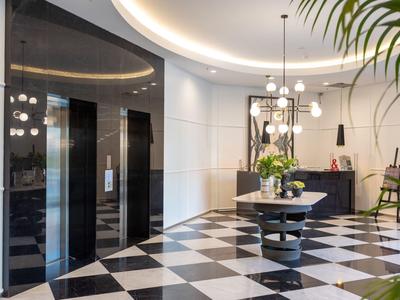 Vestíbulo de hotel elegante con piso de cuadros, ascensores de espejo y mesa redonda con plantas