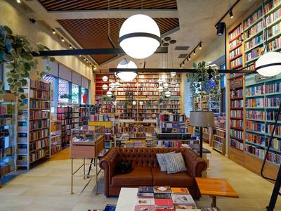 Salón de biblioteca moderno y acogedor con estanterías altas y grandes lámparas redondas.