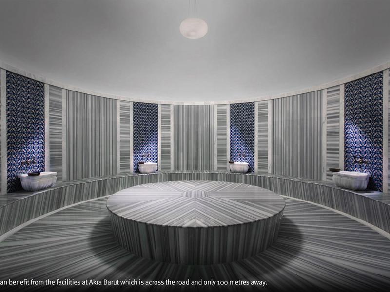 Área de spa moderna con mesa central redonda de madera y paredes azulejadas oscuras con nichos para sentarse.