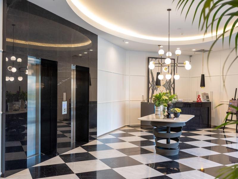 Vestíbulo de hotel elegante con piso de cuadros, ascensores de espejo y mesa redonda con plantas