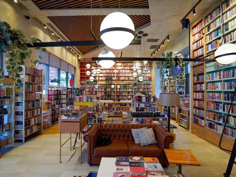 Salón de biblioteca moderno y acogedor con estanterías altas y grandes lámparas redondas.