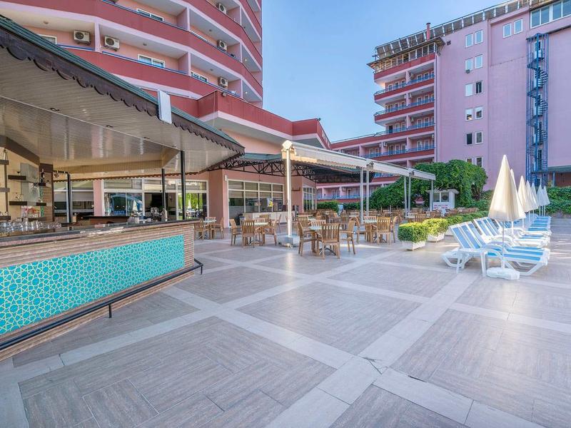 Terrasse spacieuse d'hôtel avec chaises longues, parasols et vues sur bâtiments modernes.