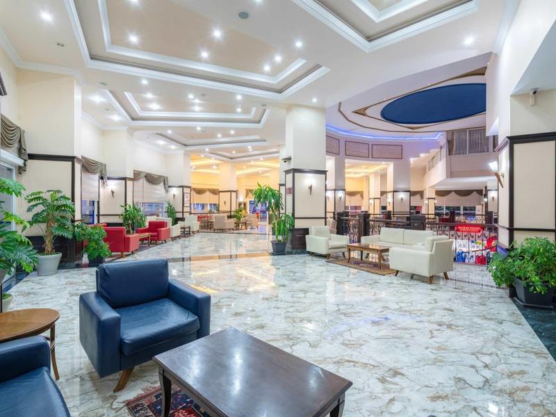 Lobby spacieux d'hôtel avec sièges modernes, sol en marbre et éclairage élégant au plafond.