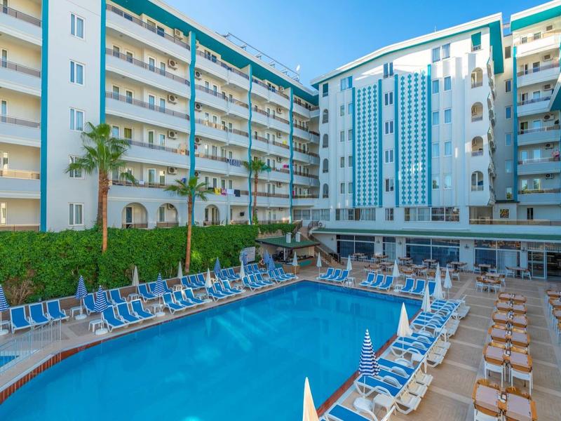 Piscine extérieure entourée de chaises longues dans un hôtel moderne à plusieurs étages.