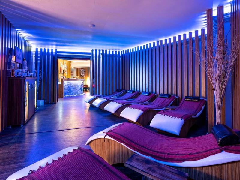 Salon détente avec chaises longues et éclairage bleu doux dans un espace moderne et paisible.