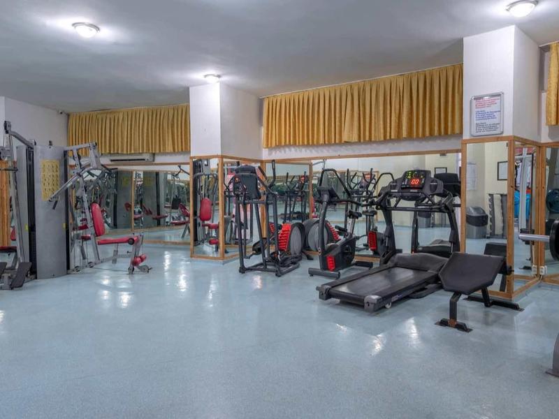 Salle de sport spacieuse avec équipements modernes et grandes fenêtres.