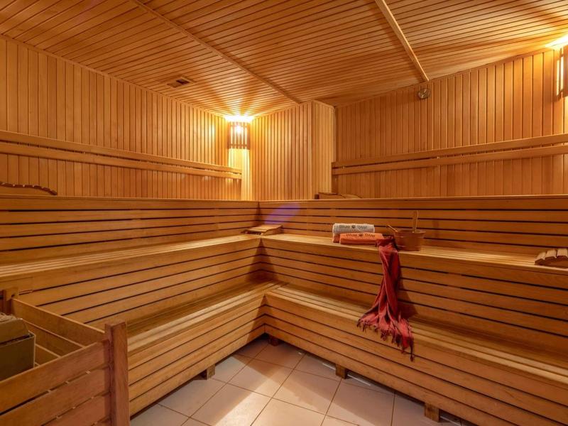 Intérieur d'un sauna en bois avec des bancs en étage et un éclairage tamisé.