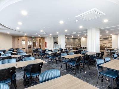 Velká moderní jídelna s mnoha stoly a židlemi v hotelu.