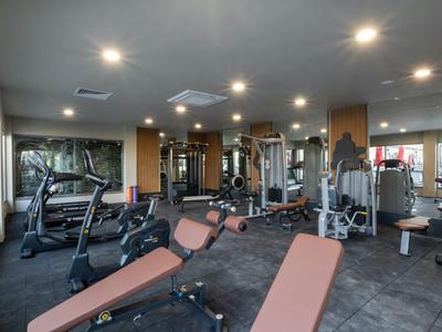 Moderne Hotel-Fitnessstudio mit Trainingsgeräten und großen Fenstern