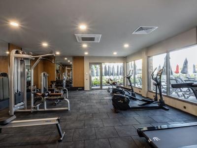 Moderner Fitnessraum mit verschiedenen Trainingsgeräten und großen Fenstern mit Ausblick.