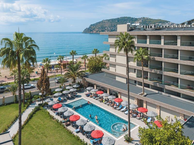 Hotel s bazénem, palmami a výhledem na moře na slunné pláži