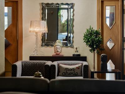Zona giorno con divani, cuscini, lampada da terra e specchio decorativo in una stanza d'hotel.