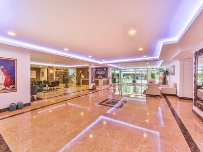 Geräumige Eingangshalle mit glänzendem Marmorfußboden, indirekter Beleuchtung und großen Fenstern.