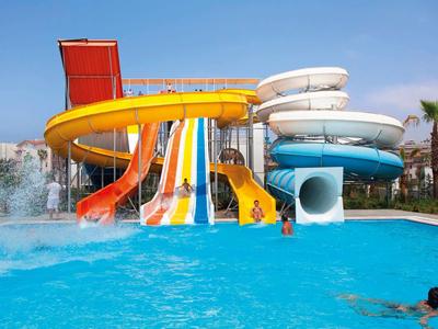 Bunte Wasserrutschen führen in einen großen blauen Pool, umgeben von Palmen und klarem Himmel.
