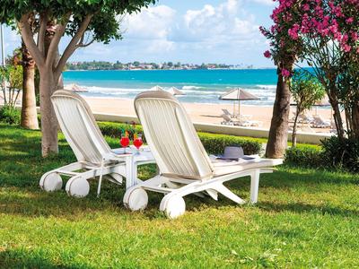 Due lettini bianchi su prato verde con vista sul mare e sulla spiaggia.