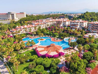 Grande complesso alberghiero con più piscine, giardini tropicali e edifici con tetti rossi.