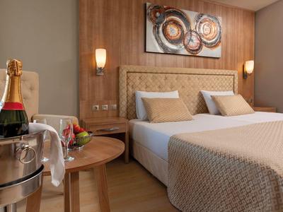 Moderní hotelový pokoj se dvěma postelemi, dřevěnými doplňky a šampaňským na stolku.