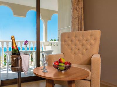 Pohodlný koutek s křeslem, miskou ovoce a šampaňským na balkóně s výhledem na moře.