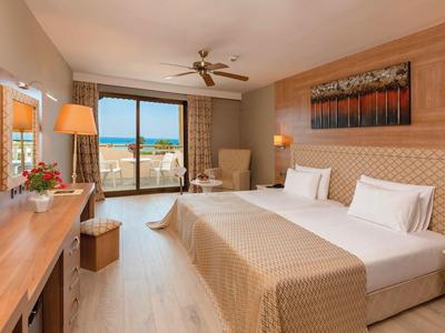 Světý hotelový pokoj s manželskou postelí, terasou a výhledem na pláž a moře.