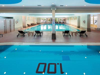 Vnitřní hotelový bazén s lehátky a značkou hloubky 100 cm na dně