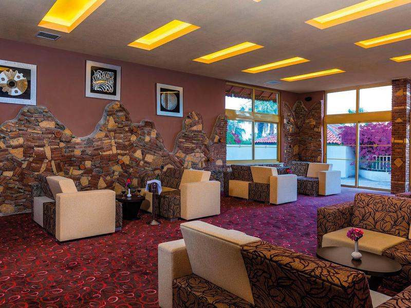 Útulná hotelová lobby s moderními křesly, kobercem a dekorativními kamennými stěnami.