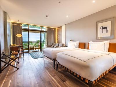 Modernes Hotelzimmer mit zwei Betten, Balkon und Blick auf die Natur.