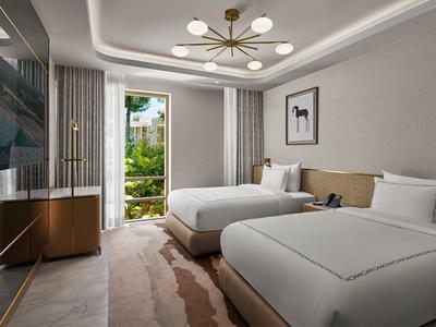 Modernes Hotelzimmer mit zwei großen Betten, großem Fenster und Balkon mit Blick ins Grüne.