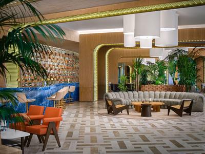 Modern eingerichteter Hotel-Loungeraum mit Pflanzen, Sitzgruppen und dekorativem Boden.