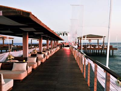 Molo z miejscami do siedzenia i daszkami rozciąga się nad morzem o zachodzie słońca.