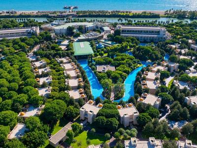 Luftaufnahme eines großen Resorts mit Pool, vielen Bäumen und Gebäuden nahe dem Meer.