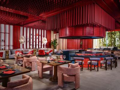 Nowoczesna restauracja hotelowa w czerwonych i różowych tonacjach z eleganckimi miejscami do siedzenia.