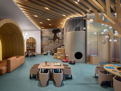 Moderne speelruimte voor kinderen in hotel met houten plafond, zitplaatsen en kleurrijk speelgoed.