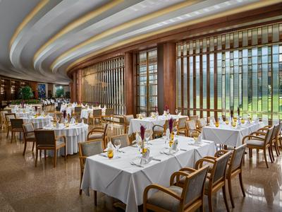 Elegant restaurant met witte tafelkleden, houten stoelen en grote ramen met uitzicht op bergen.