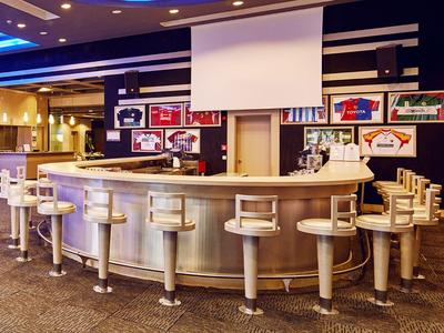 Moderne hotelbar met ronde toog en witte barkrukken voor kleurrijke wanddecoraties.