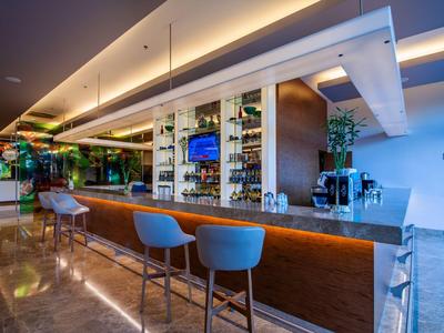 Moderne hotelbar met verlichte toog, blauwe barkrukken en zachte plafondverlichting