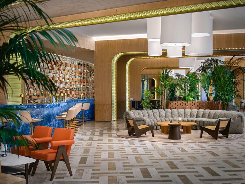 Modern eingerichteter Hotel-Loungeraum mit Pflanzen, Sitzgruppen und dekorativem Boden.