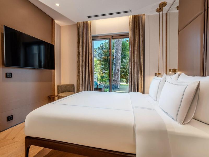 Modernes Hotelzimmer mit gemütlichem Doppelbett, großem Fenster und Flachbildfernseher.