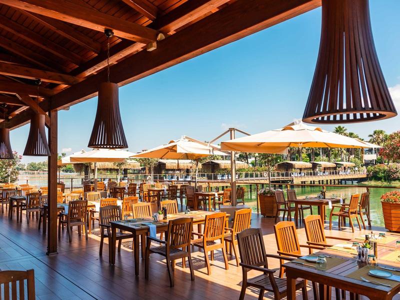 Außergewöhnliche Terrasse mit bestuhltem Essbereich und großen Sonnenschirmen bei klarem Himmel.