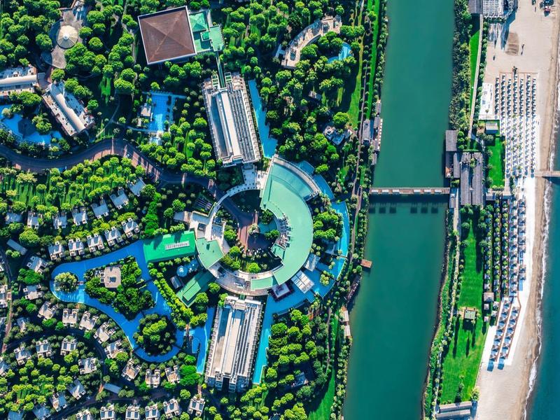 Luftaufnahme eines Resorts mit Pool, Fluss und Strand am Meer