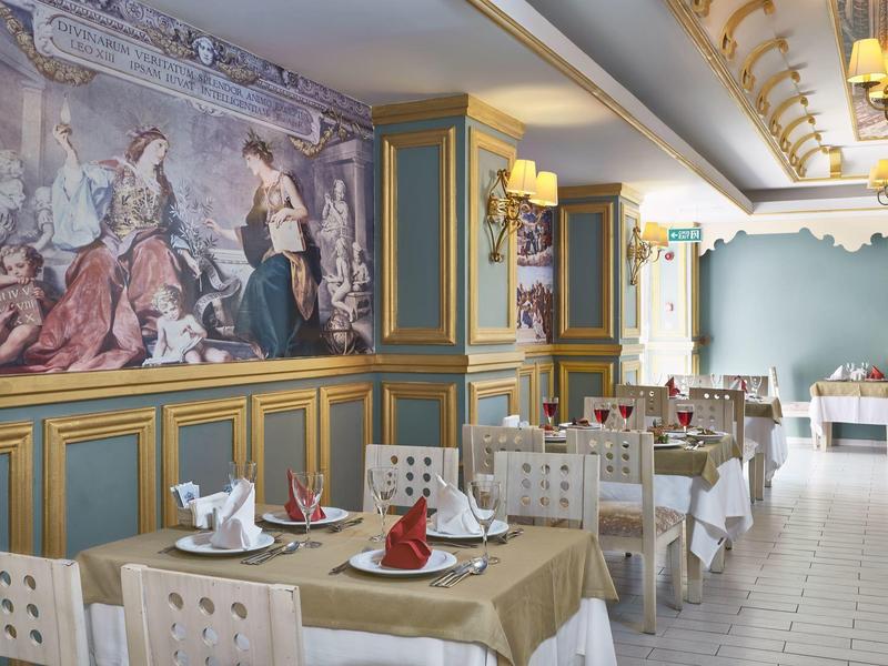 Salle à manger élégante avec fresque classique et tables dressées dans un hôtel.